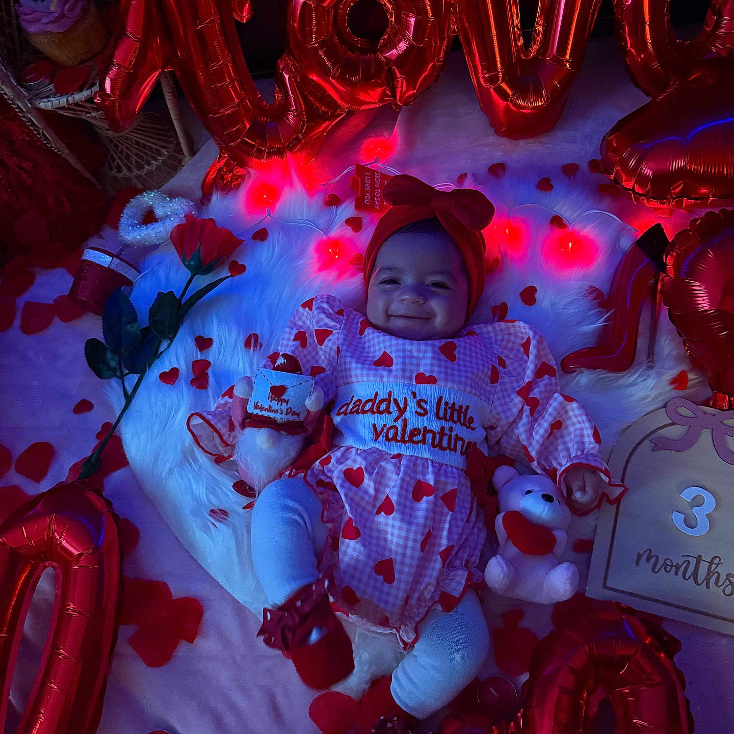 Leylani joined the competition — help win amazing prizes! baby, bow, celebration, foil_balloons, fur_rug, headband, heart_pattern, holiday_decor, infant, milestone_card, outfit, petals, photo_shoot, plush_toy, red_balloons, rose, smile, soft_lighting, teddy_bear, valentine