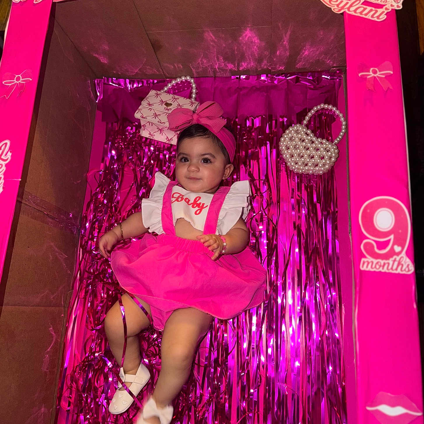 Leylani is registered to the contest to win money with this photo: accessories, baby, birthday, box, bracelet, celebration, child, cute, decoration, girl, headband, indoors, infant, party, pink, portrait, ribbon, shoes, smile, toddler