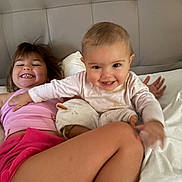 Camille participe au concours pour gagner de l'argent avec cette photo : child, baby, smiling, bed, pillow, happy, playful, indoor, person, headboard, clothing, pink_shirt, white_pajamas, young_child, candid, family, toddler, cute, sibling, fun