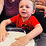 child, dough, flour, table, red_shirt, smiling, adult, brick_wall, kitchen, hands, cooking, fun, happy, indoor, person, preparation, youth, playful, food, family