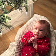 Sarah is registered to the contest to win money with this photo: baby, infant, red_onesie, polka_dots, blanket, christmas_tree, tree_lights, holiday, indoors, wood_floor, cute, child, portrait, soft_texture, warm_lighting, seasonal, festive, toddler, face, expression