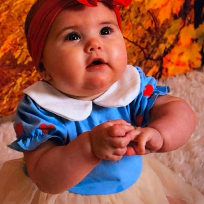 Isla-Grace is registered to the contest to win money with this photo: autumn, baby, background, blue_clothing, bow, child, chubby_cheeks, curious, cute, expression, face, hands, indoors, leaves, portrait, red_headband, sitting, toddler, tutu, young_child