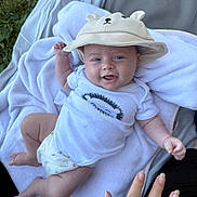 Clément a rejoint le concours — aidez-le/la à gagner de superbes lots ! baby, infant, smile, hat, onesie, diaper, blanket, towel, grass, outdoor, hand, foot, face, blue_eyes, portrait, lying_down, cute, cozy, baby_clothing, soft