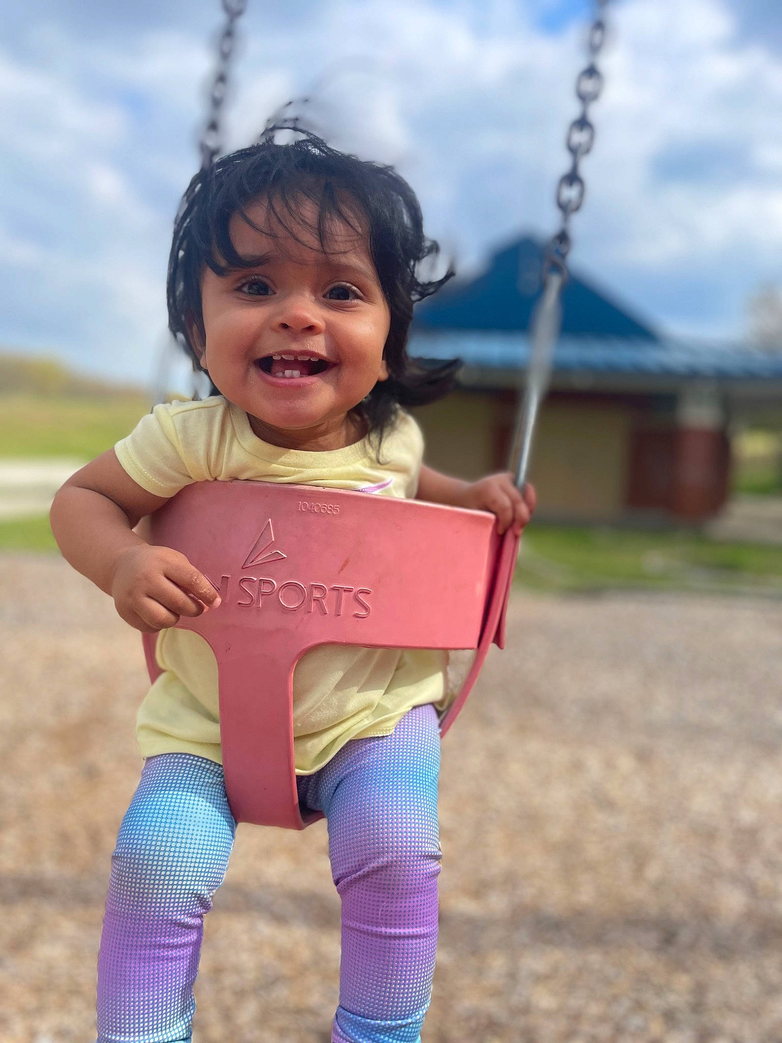 Lyra is registered to the contest to win money with this photo: baby_toddler_clothing, child, cloud, eye, fun, grass, grassland, hand, happy, joy, leisure, outdoor_play_equipment, people_in_nature, person, skin, sky, smile, sock, swing, t_shirt