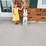brick_wall, child, decoration, door, easter_bunny, eggs, footwear, girl, happy, holiday, outdoor, person, porch, shutter, sidewalk, smiling, spring, summer, window, yellow_dress