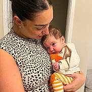 Odette is registered to the contest to win money with this photo: woman, baby, holding, indoor, leopard_print, striped_pants, orange_slippers, affection, love, closeup, portrait, casual_clothing, child, family, tenderness, skin, head, face, person, human