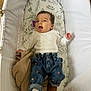 Odette is registered to the contest to win money with this photo: baby, infant, bassinet, blanket, clothing, denim, footwear, heart_pattern, indoor, infant_clothing, knitted_blanket, laying_down, mattress, open_mouth, person, plush, sleeping_area, white, wood_floor, young_child