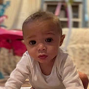 Harley is registered to the contest to win money with this photo: baby, infant, child, face, eyes, white_clothing, crawling, indoor, blurred_background, furniture, toy, curious, young, portrait, head, skin, expression, person, cute, closeup