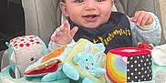 Lowan a rejoint le concours — aidez-le/la à gagner de superbes lots ! baby, bib, bottle, cheerful, child, clothing, curly_hair, face, foot, hand, happy, high_chair, indoor, person, playful, seat, smiling, soft_toys, table, toys