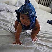 Kea joined the competition — help win amazing prizes! baby, child, crawling, blue_hood, bed, bedroom, pillow, blanket, infant, cute, curious, person, indoors, furniture, headwear, playful, skin, young_child, expression, clothing