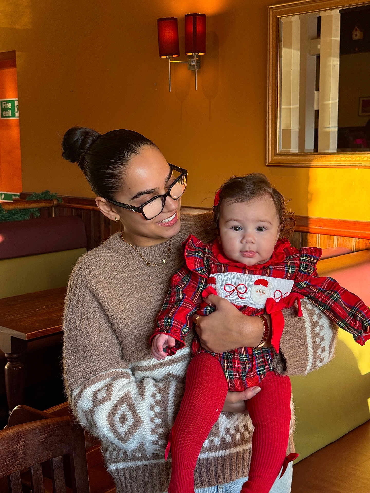 Alina Luellè joined the competition — help win amazing prizes! woman, baby, indoor, holding, smiling, plaid_dress, red_tights, glasses, sweater, wooden_table, bench, warm_lighting, mirror, wall_lamp, happy, person, child, family, cozy, casual_clothing