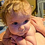 Charles is registered to the contest to win money with this photo: baby, child, infant, curly_hair, blue_eyes, skin, arm, hand, face, person, indoor, resting, adult, torso, closeup, expression, cute, soft_light, intense_gaze, tender_moment