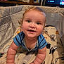 Charles is registered to the contest to win money with this photo: baby, child, crawling, playpen, blanket, indoor, smiling, happy, face, person, blue_shirt, curly_hair, cute, skin, hand, arm, furniture, shelf, container, television