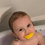 baby, child, bathtub, water, toy, yellow_toy, smile, wet_hair, face, skin, eyes, chewing, sitting, indoor, cute, happy, bath, childhood, play, closeup