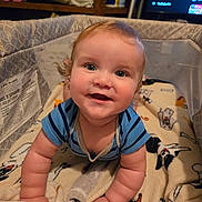 Charles is registered to the contest to win money with this photo: baby, child, crawling, playpen, blanket, indoor, smiling, happy, face, person, blue_shirt, curly_hair, cute, skin, hand, arm, furniture, shelf, container, television