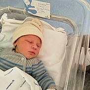 Louis participe au concours pour gagner de l'argent avec cette photo : newborn, baby, sleeping, hospital, bassinet, blanket, hat, clothing, infant, person, indoors, bed, pale_skin, blue_floor, white_gloves, knitwear, portrait, peaceful, resting, hospital_bed