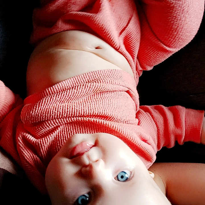 Michelle joined the competition — help win amazing prizes! baby, blue_eyes, child, closeup, cute, expression, face, head, human, indoors, infant, long_sleeve, lying_down, newborn, person, pink_clothing, portrait, skin, smooth_skin, soft_light