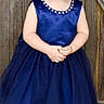 Harley is registered to the contest to win money with this photo: toddler, child, girl, blue_dress, white_shoes, bows, curly_hair, hair_clip, standing, wooden_background, outdoor, portrait, rosy_cheeks, cute, fashion, smiling, person, young_child, innocence, casual