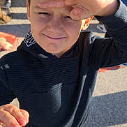 Ezio a rejoint le concours — aidez-le/la à gagner de superbes lots ! child, boy, outdoor, sunlight, hoodie, sneakers, smiling, playful, person, casual_clothing, daylight, young, standing, gesture, face, hand, expression, shadow, pavement, background_people