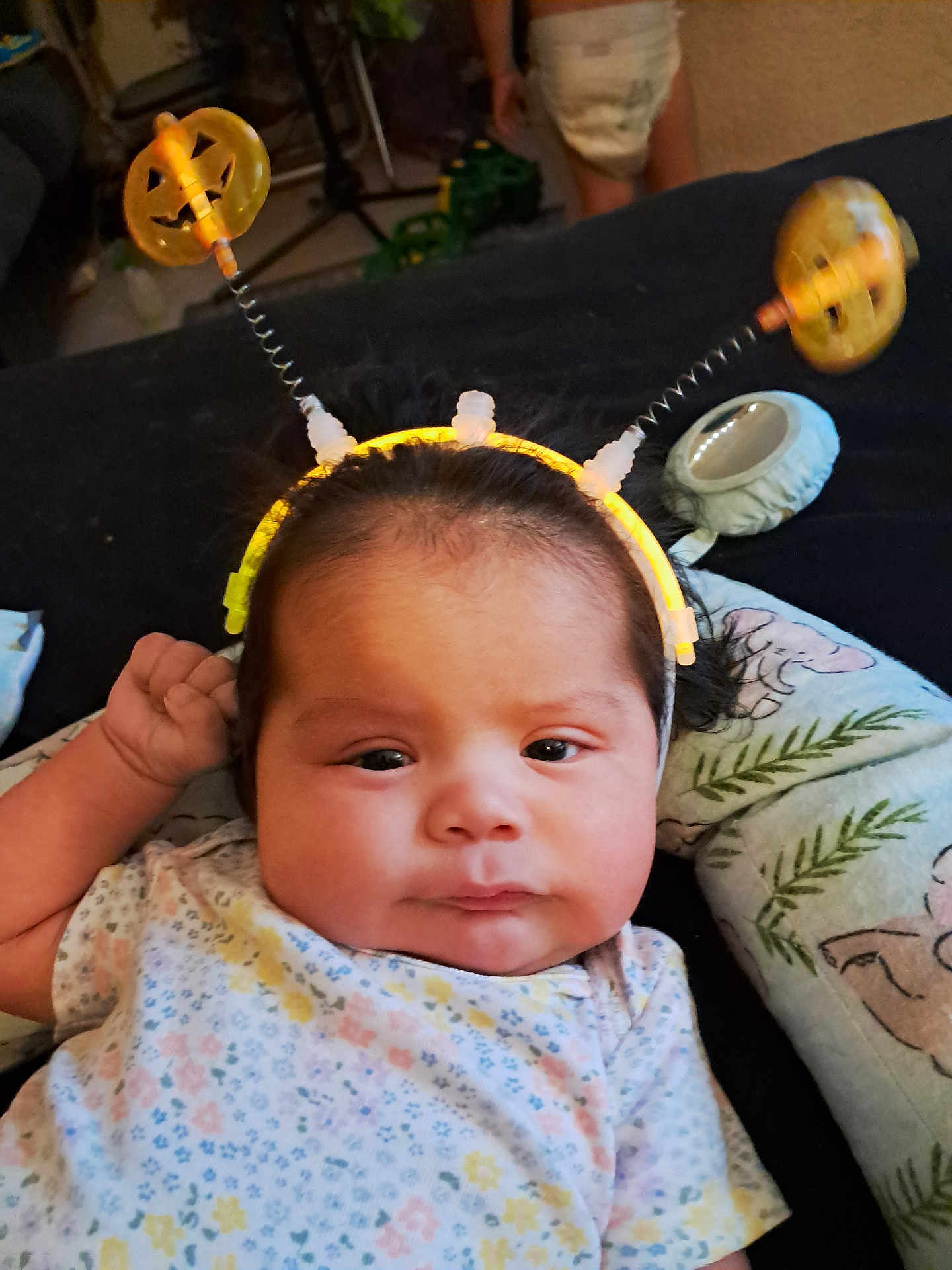 Macrista joined the competition — help win amazing prizes! baby, black_hair, child, clothing, cute, expression, face, floral_pattern, glowing, halloween, hand, headband, indoors, infant, lying_down, person, pillow, pumpkin, soft_lighting, young