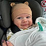 baby, infant, car_seat, hat, bear_ears, blanket, pacifier, smiling, face, child, person, hand, nail_art, clothing, warm, cozy, indoor, cute, seatbelt, closeup