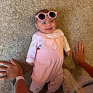 Riella joined the competition — help win amazing prizes! baby, pink_sunglasses, pink_outfit, carpet, hands, sneaker, smiling, lying_down, cute, infant, child, person, indoor, happy, fashion, accessory, footwear, casual, portrait, skin
