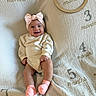 baby, infant, smile, headband, pink_socks, blanket, months_marker, wooden_ring, cute, happy, sitting, child, clothing, portrait, indoors, soft_texture, milestone, young_child, face, celebration