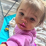 Aurora is registered to the contest to win money with this photo: toddler, child, pink_clothing, messy_face, food, frosting, indoor, blanket, toy, curious, close_up, portrait, baby, face, expression, candid, person, young_child, sleeve, hand