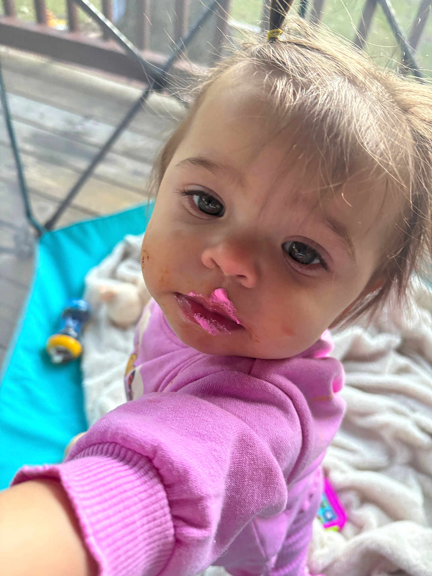 Aurora is registered to the contest to win money with this photo: toddler, child, pink_clothing, messy_face, food, frosting, indoor, blanket, toy, curious, close_up, portrait, baby, face, expression, candid, person, young_child, sleeve, hand
