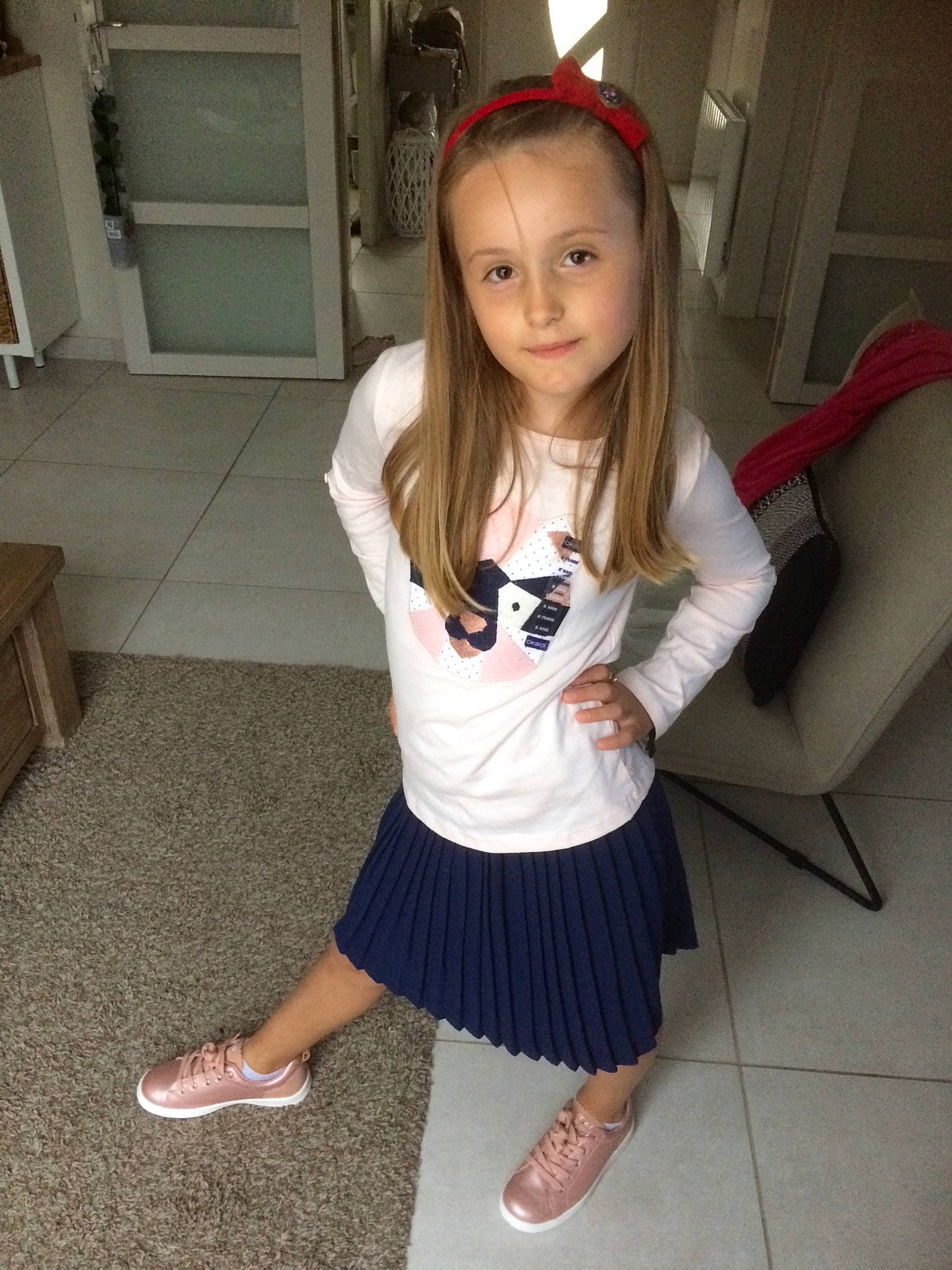 Emma participe au concours pour gagner de l'argent avec cette photo : ankle, baby_toddler_clothing, calf, child_model, clothing, couch, door, floor, foot, hair_accessory, hair_tie, headband, headpiece, hime_cut, human_leg, long_hair, person, pigtail, skort