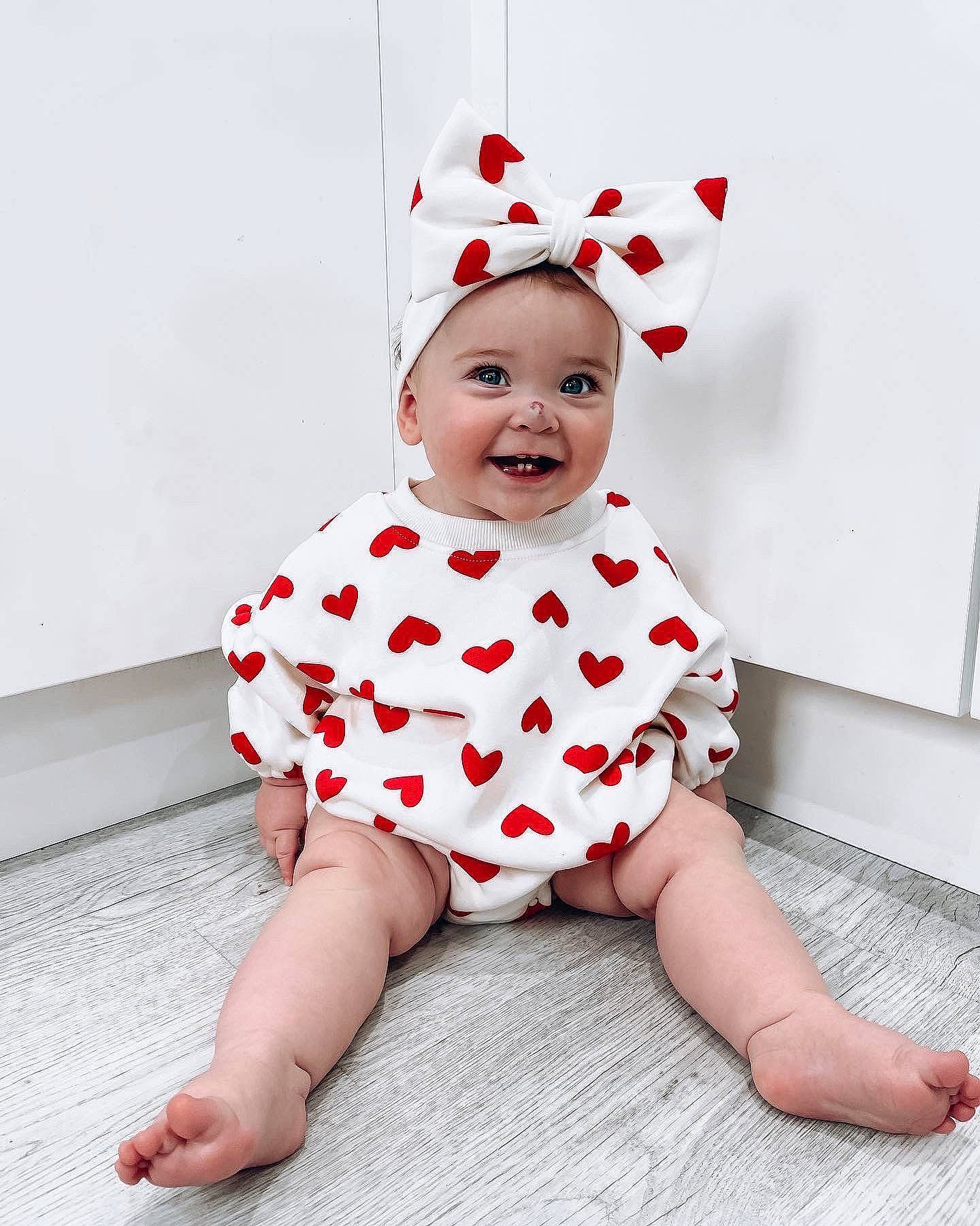 Hali is registered to the contest to win money with this photo: baby, baby_toddler_clothing, child, collar, costume_hat, dress, face, flooring, foot, fun, happy, head, headgear, headwear, human_body, joy, pattern, person, sitting, sleeve