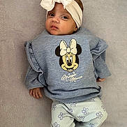 Aleena joined the competition — help win amazing prizes! baby, child, infant, headband, bow, clothing, sweater, minnie_mouse, pants, flower_pattern, blanket, soft_texture, lying_down, looking_at_camera, cute, smirk, indoor, portrait, person, cozy