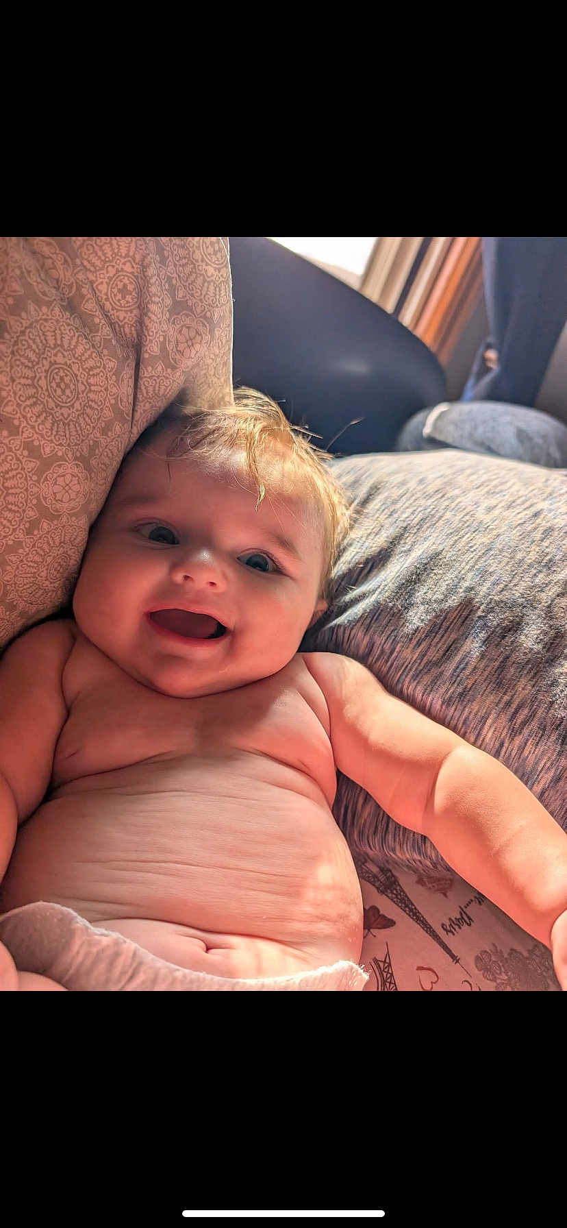 Knox is registered to the contest to win money with this photo: baby, smiling, happy, infant, cute, skin, face, arm, pillow, blanket, indoors, natural_light, child, portrait, closeup, comfortable, relaxed, couch, warm, expression