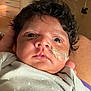 baby, infant, face, curly_hair, nasal_tube, hospital, medical_equipment, polka_dot_clothing, newborn, person, skin, eyes, hand, healthcare, patient, indoors, closeup, care, lying_down, adult_hand
