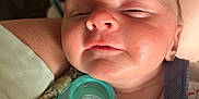 Rylie is registered to the contest to win money with this photo: baby, infant, sleepy, pacifier, blanket, closeup, face, skin, child, newborn, comfort, cuddle, soft, resting, person, human, nap, indoors, warm_light, cozy