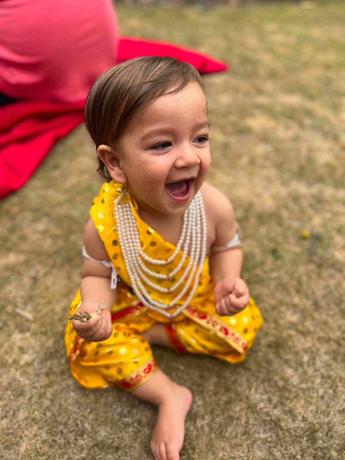 Nirvair is registered to the contest to win money with this photo: toddler, child, smiling, yellow_clothing, traditional_dress, pearls, grass, outdoor, happy, laughing, barefoot, sitting, hands, face, young_child, nature, daylight, cute, joyful, playful