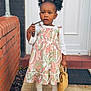 toddler, child, curly_hair, bow, dress, paisley_pattern, sunglasses, handbag, white_long_sleeve, tights, shoes, doorstep, brick_wall, doormat, outdoor, standing, person, fashion, cute, portrait