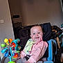 baby, child, smiling, pink_clothing, bib, toy, high_chair, indoor, face, happy, seat, furniture, colorful, play, person, infant, cheerful, young_child, home, accessory