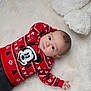 baby, child, mickey_mouse, red_sweater, plush_toy, teddy_bear, white_rug, cute, indoor, portrait, infant, clothing, holiday_theme, soft_texture, lying_down, casual, young_child, smiling, cozy, comfortable