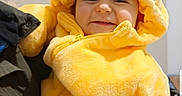 Tyam a rejoint le concours — aidez-le/la à gagner de superbes lots ! baby, casual, child, closeup, cozy, cute, face, fluffy, happy, heart_patches, hood, indoor, infant, jacket, person_holding, portrait, smiling, soft_texture, warm_clothing, yellow_onesie