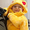 baby, casual, child, closeup, cozy, cute, face, fluffy, happy, heart_patches, hood, indoor, infant, jacket, person_holding, portrait, smiling, soft_texture, warm_clothing, yellow_onesie