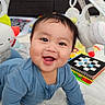 arch, baby, baby_toys, blue_onesie, cheerful, child, colorful, crawling, cute, early_development, face, happy, indoors, infant, playmat, plush_toys, smiling, soft_blanket, toys, young_child