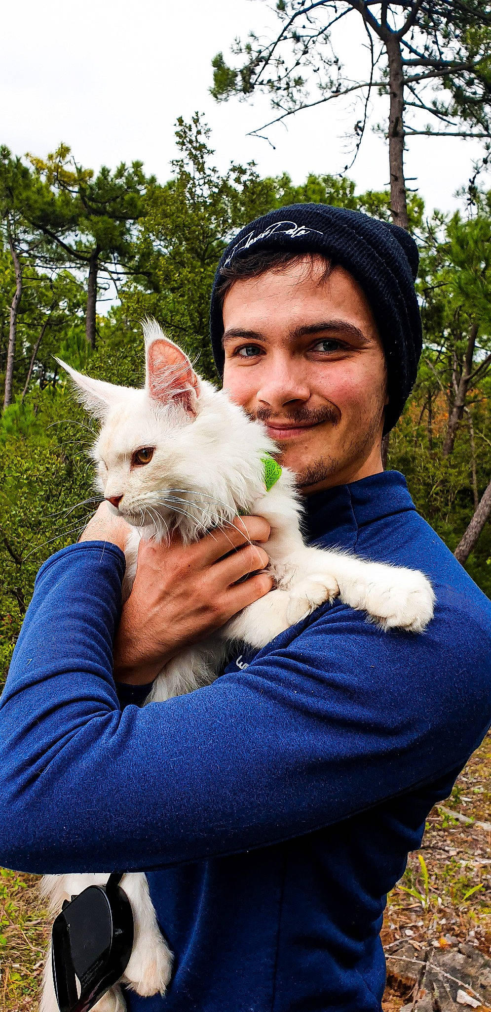 Aslan a rejoint le concours — aidez-le/la à gagner de superbes lots ! beard, cap, carnivore, cat, companion_dog, facial_hair, fawn, felidae, gesture, grass, hand, happy, hat, people_in_nature, plant, sky, small_to_medium_sized_cats, smile, tree, whiskers
