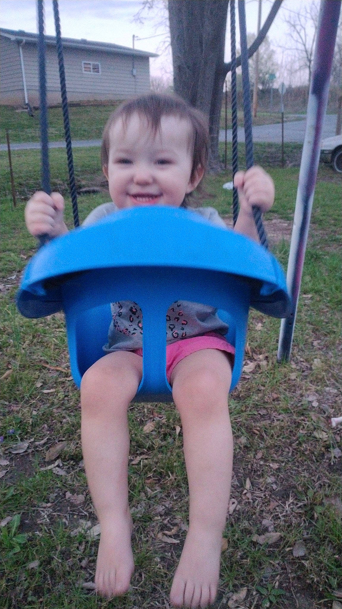 Lillian is registered to the contest to win money with this photo: baby_toddler_clothing, barefoot, child, electric_blue, face, foot, fun, grass, happy, head, joy, leisure, outdoor_play_equipment, people_in_nature, person, plant, play, playground, sitting, smile