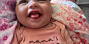 Violet is registered to the contest to win money with this photo: baby, smiling, infant, onesie, blanket, floral_pattern, happy, cute, tongue_out, person, child, indoors, home, arm, clothing, face, head, seated, cozy, soft