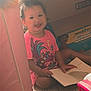 toddler, child, smiling, pink_shirt, book, carpet, box, homestyle_seasoned_croutons, swaddlers_box, indoor, play_area, sitting, happy, person, cute, young_child, floor, reading, toy_storage, casual_clothing