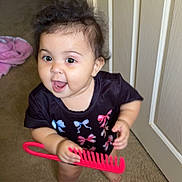 Nova joined the competition — help win amazing prizes! baby, child, barefoot, carpet, comb, door, floor, hair, indoors, person, shirt, smiling, standing, toy, young_child, playful, happy, colorful_clothing, pink, black_shirt