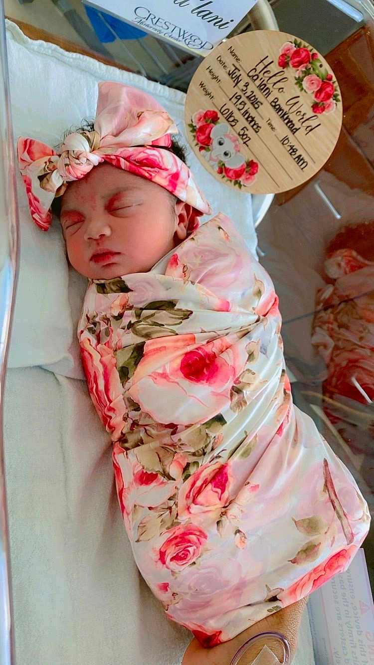 Calani is registered to the contest to win money with this photo: newborn, baby, infant, sleeping, swaddled, floral, pink, headband, hospital, bassinet, blanket, face, person, cute, resting, peaceful, birth_announcement, wooden_plaque, decorations, koala
