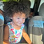 child, toddler, curly_hair, afro, smiling, colorful_dress, floral_pattern, sunlight, car_interior, seat, hand, portrait, happy, cute, person, indoors, daylight, skin, young_child, people