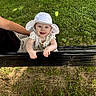 baby, child, hat, white_clothing, polka_dot, bench, black_bench, grass, park, outdoor, sunlight, smiling, happy, person, arm, nature, daylight, cute, infant, support